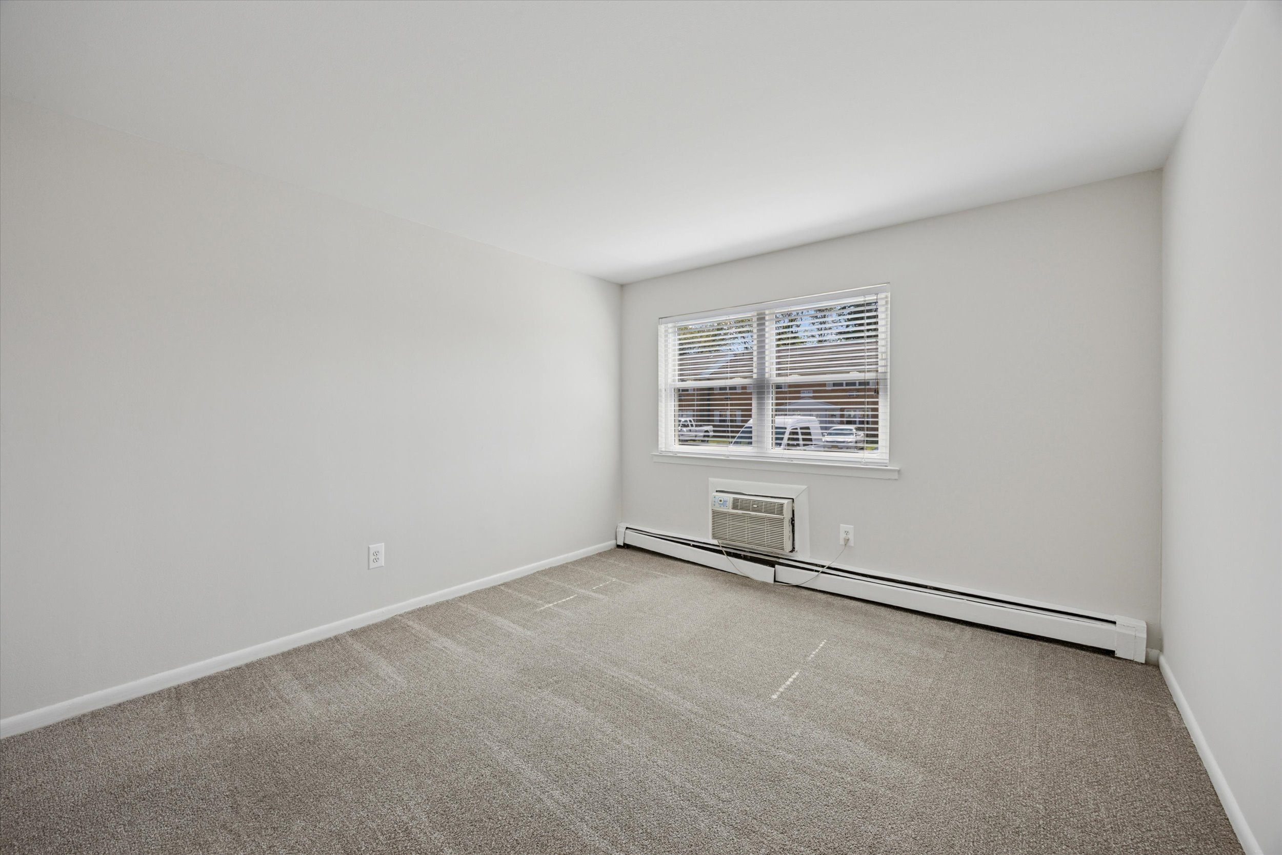 A room with a window and a carpeted floor.